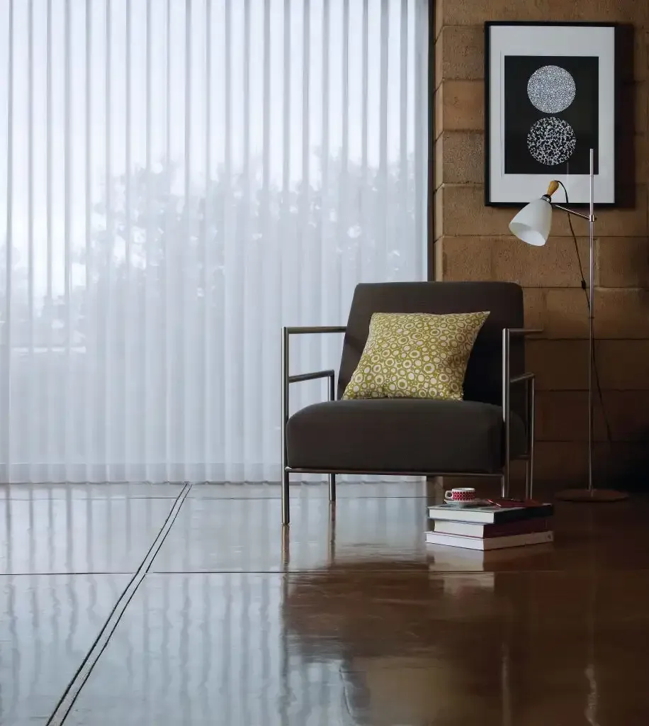 A modern living space with an armchair, floor lamp, and window with vertical blinds.