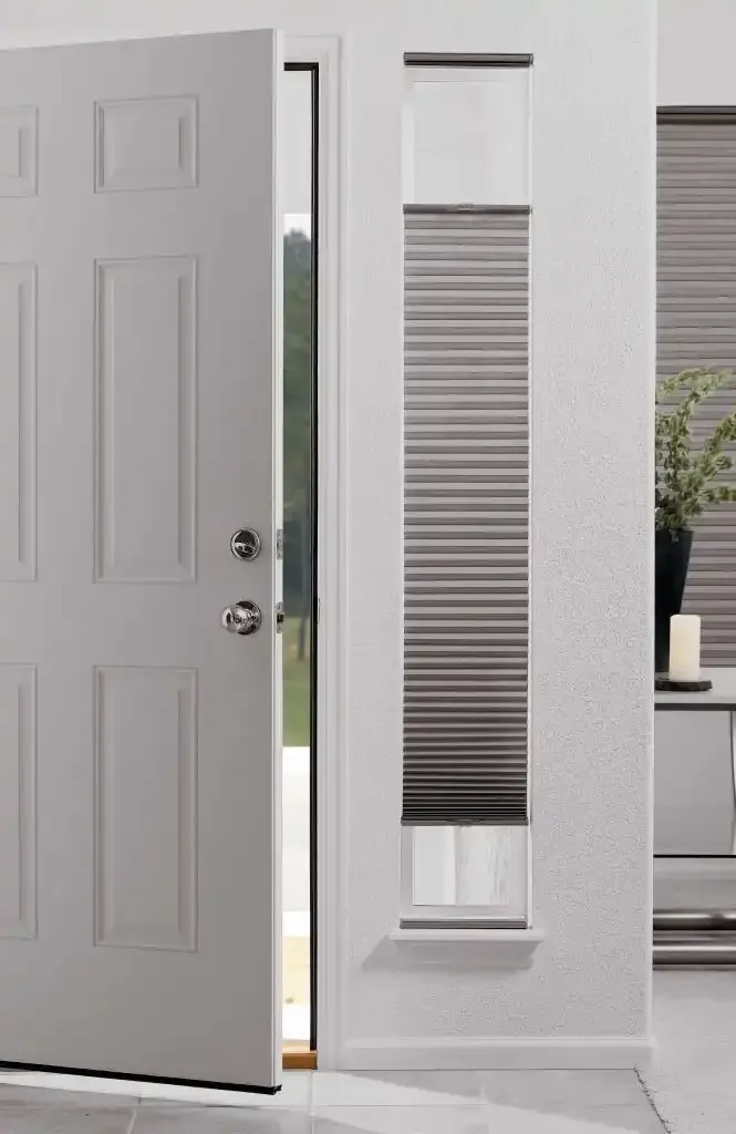 Open white front door beside a narrow sidelight window with a gray cellular shade