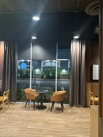 Floor-to-ceiling gray drapery panels framing storefront windows in a cafe seating area at night