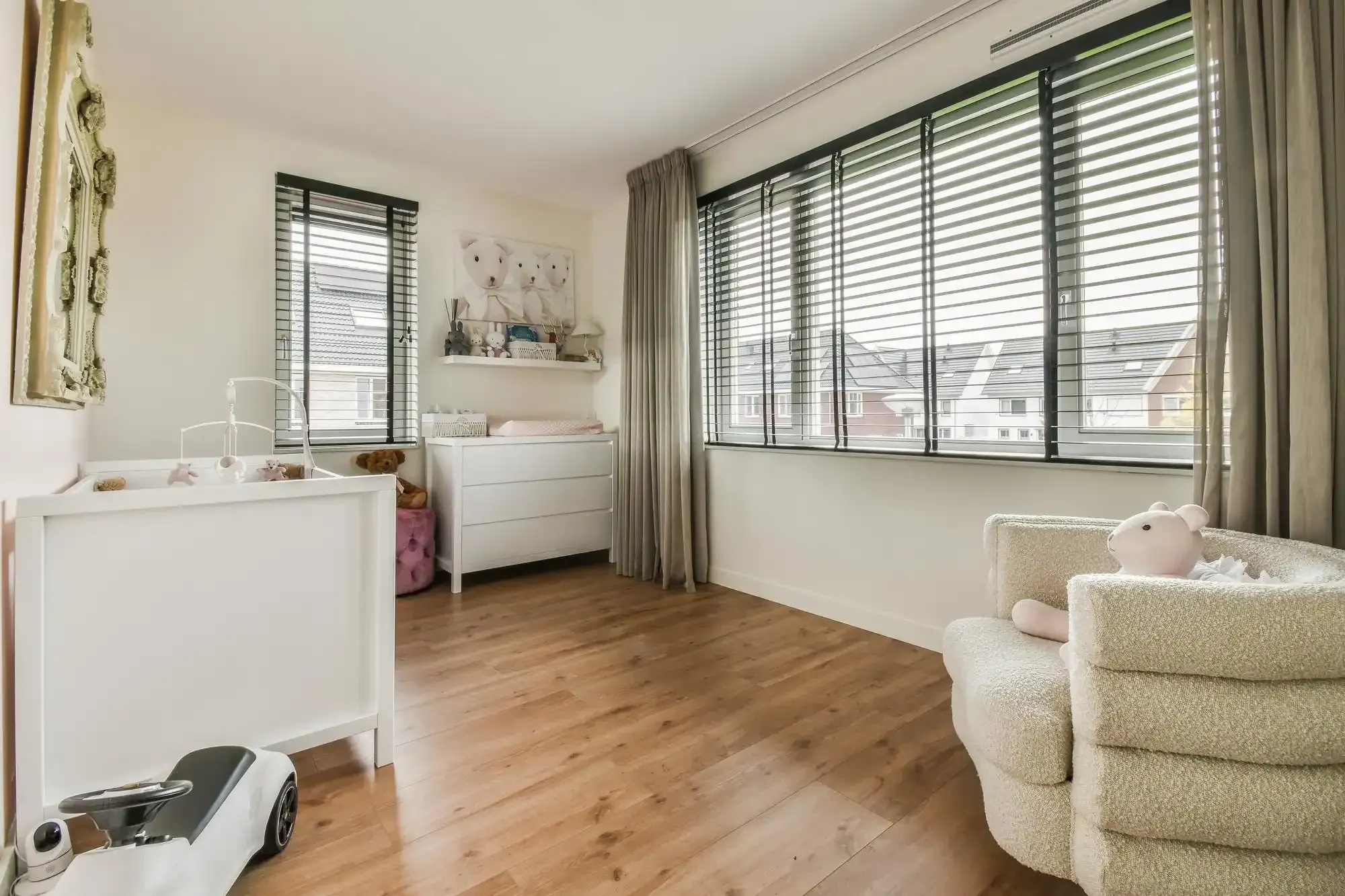 Nursery with tall windows covered by dark horizontal blinds