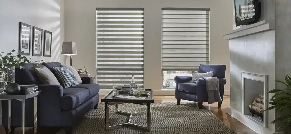 Living room with a blue sofa, fireplace, and white dual shades on two windows
