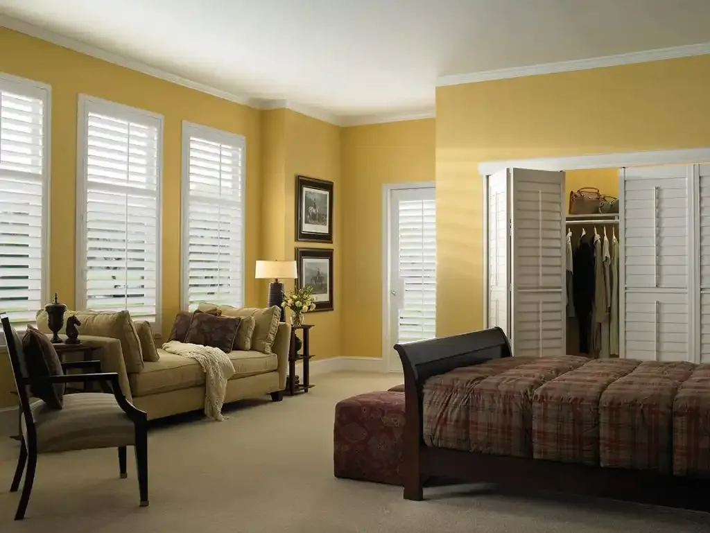 Yellow bedroom with white plantation shutters on the windows