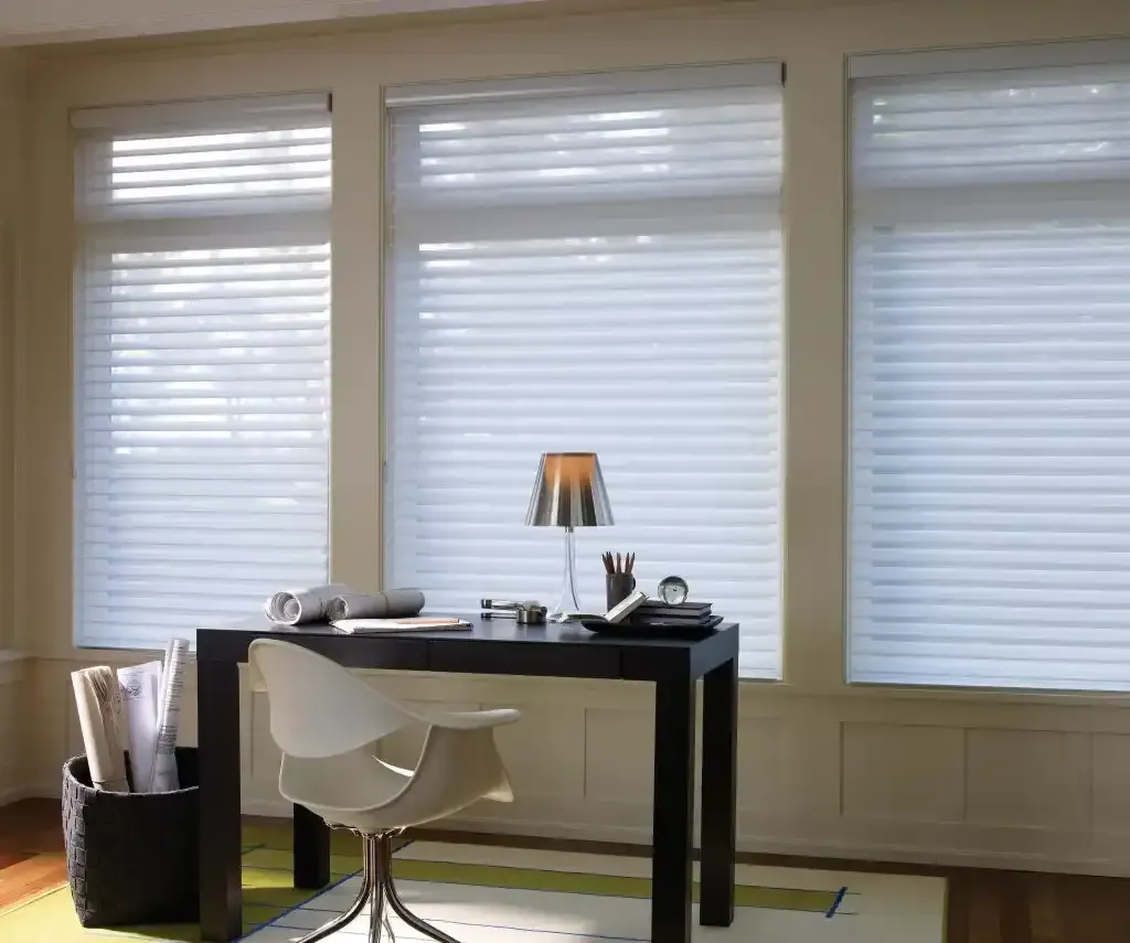 Home office with a black desk and white sheer shadings on three large windows