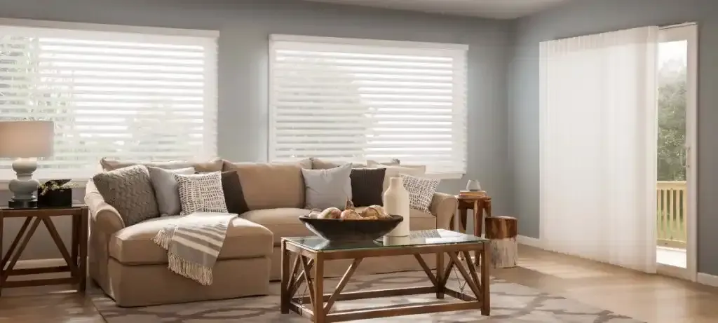 Living room with a beige sectional and white sheer shadings on windows and a patio door