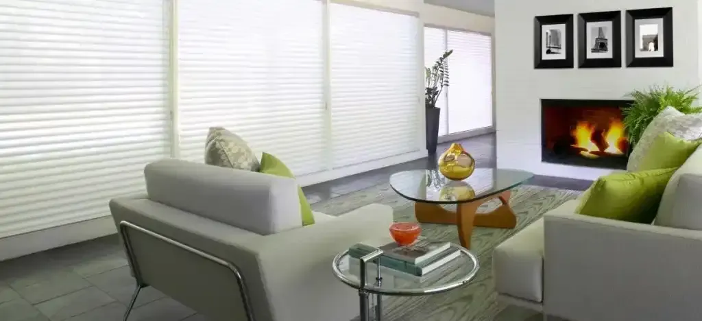 Modern living room with white sofas, a fireplace, and white sheer shadings on a wall of windows