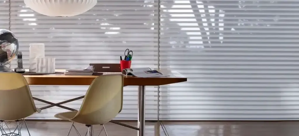 Modern office with a wood desk, two chairs, and white sheer shadings on a window wall