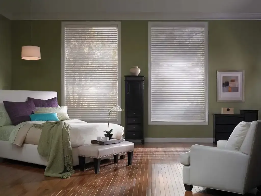 Bedroom with olive green walls and white sheer shadings on two tall windows