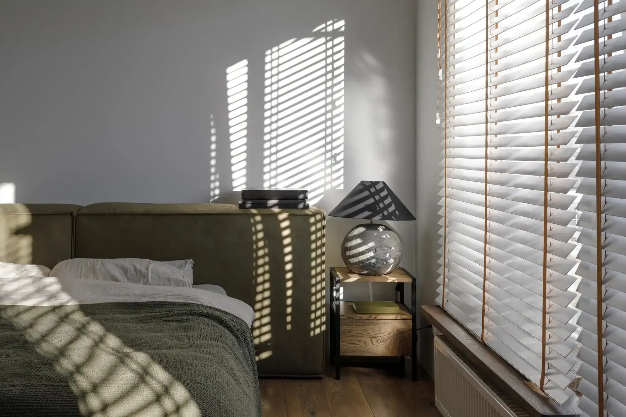 Bedroom window with white wood blinds mounted inside the frame